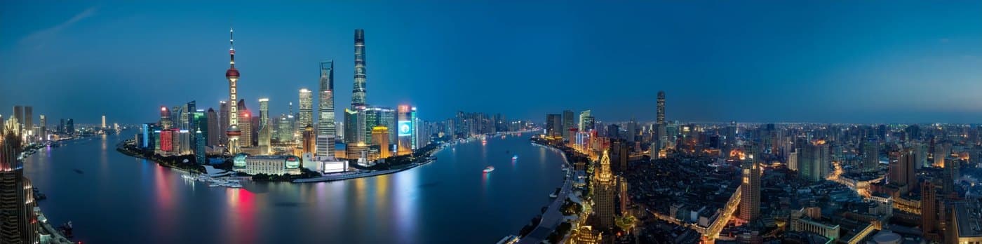 MOSS-Image: A wide night panorama of the Shanghai skyline along the Huangpu River, with lit towers reflected in the water